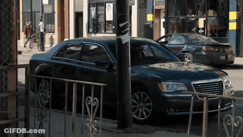 A Black Chrysler Car Is Parked On The Side Of The Street GIF