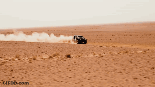 A Black Dacia Car Is Driving Through The Desert GIF
