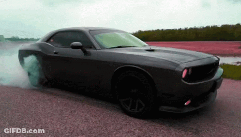 A Black Dodge Challenger Is Doing A Burnout On The Road GIF