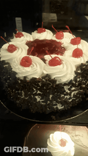 A Black Forest Cake With Whipped Cream And Cherries GIF