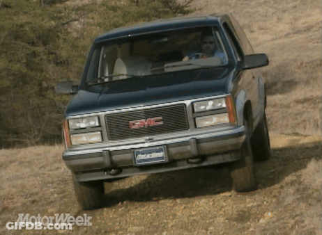 A Black Gmc Truck Is Driving Down A Dirt Road GIF