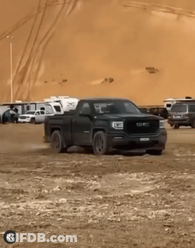 A Black Gmc Truck Is Driving Through The Dirt GIF