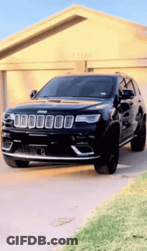 A Black Jeep Is Parked In Front Of A Garage Door GIF