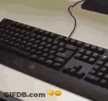 A Black Keyboard Is Sitting On Top Of A White Table Next To Two Smiley Faces . GIF