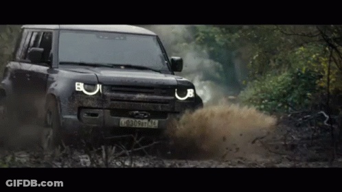 A Black Land Rover Defender Is Driving Through A Muddy Area GIF