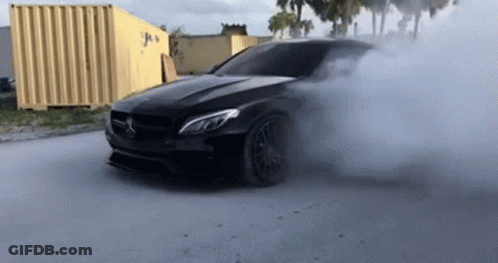 A Black Mercedes Benz Is Doing A Burnout On A Road . GIF