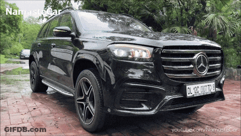 A Black Mercedes Is Parked On A Brick Driveway With A Namaste Car Logo In The Background GIF