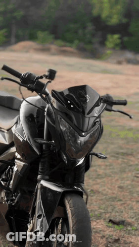 A Black Motorcycle Is Parked In A Field GIF