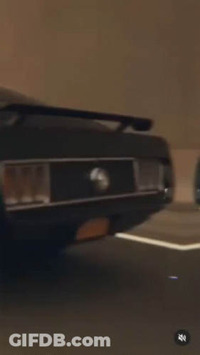 A Black Mustang Is Driving Down A Highway At Sunset . GIF