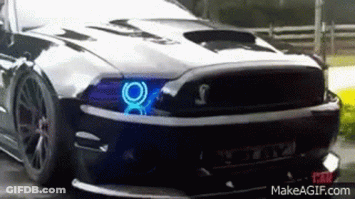 A Black Mustang With Blue Lights On The Headlights GIF