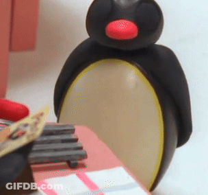 A Black Penguin With A Red Beak Is Sitting On A Table GIF