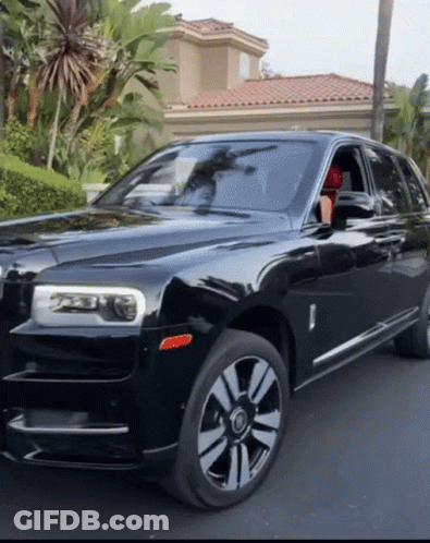 A Black Rolls Royce Car Is Parked In Front Of A House GIF