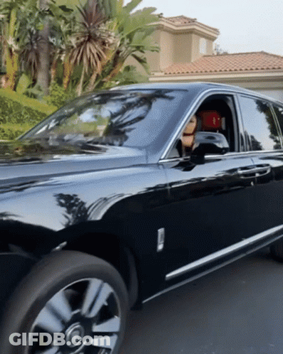 A Black Rolls Royce Is Parked In A Driveway In Front Of A House GIF