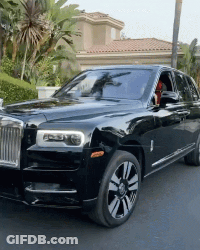 A Black Rolls Royce Is Parked In Front Of A Palm Tree GIF