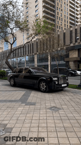 A Black Rolls Royce Is Parked On The Sidewalk In Front Of A Building GIF