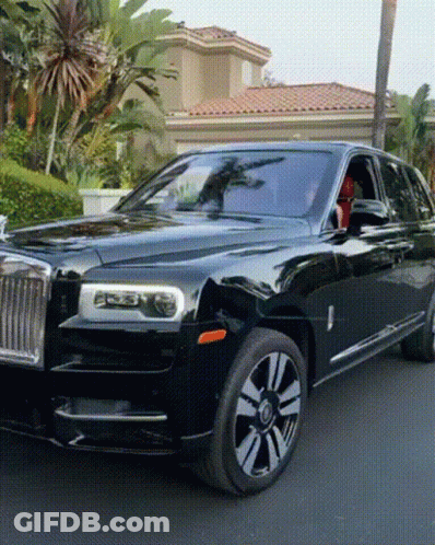 A Black Rolls Royce Is Parked On The Street In Front Of A House GIF