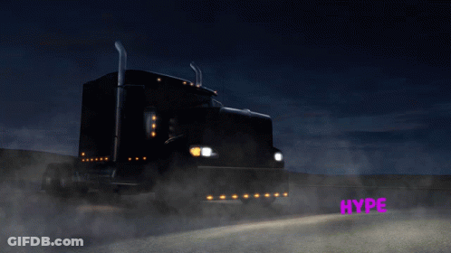 A Black Semi Truck Is Driving Down A Highway At Night GIF