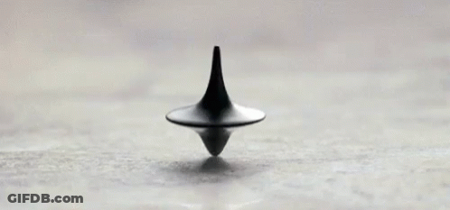 A Black Spinning Top Is Sitting On Top Of A White Surface . GIF