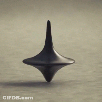 A Black Spinning Top Is Spinning On A Table . GIF