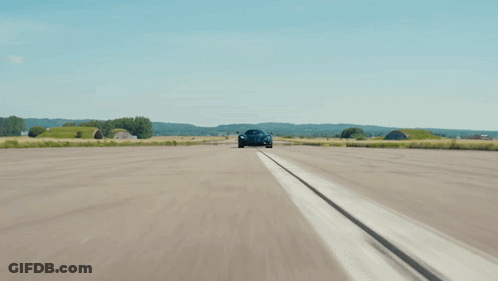 A Black Sports Car Is Driving Down The Road GIF