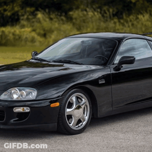 A Black Sports Car Is Parked On A Road GIF