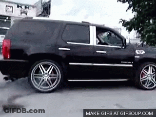 A Black Suv Is Parked In Front Of A Building That Says Gm On It GIF