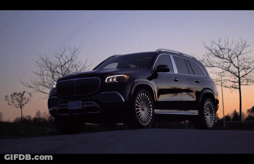 A Black Suv Is Parked On The Side Of A Road With Trees In The Background GIF