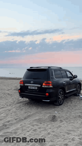A Black Toyota Suv Is Parked On A Sandy Beach With A License Plate That Says Bscn 888 GIF