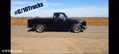 A Black Truck Is Driving Down A Dirt Road With A # C / 10Trucks Sticker Above It GIF