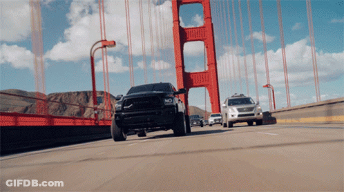 A Black Truck Is Driving Over A Bridge GIF