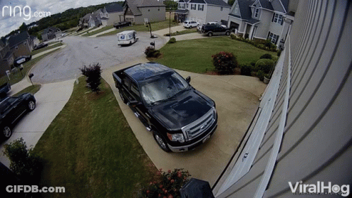 A Black Truck Is Parked In Front Of A House With A Ring.com Logo GIF