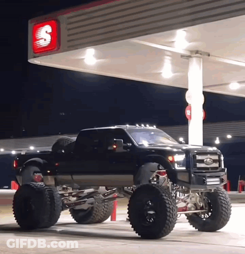 A Black Truck Is Parked Under A Gas Pump At A Gas Station GIF