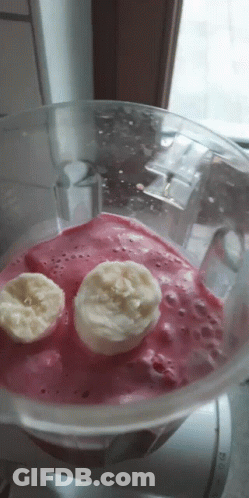 A Blender Filled With A Pink Smoothie With Two Banana Slices In It GIF