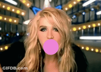 A Blonde Woman Blowing A Pink Bubble With A Butterfly In The Background GIF
