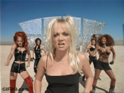 A Blonde Woman In A Black Top Stands In Front Of A Group Of Dancers GIF