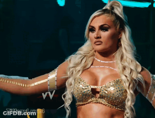 A Blonde Woman In A Gold Top With The Letters Vv On The Bottom GIF