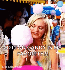 A Blonde Woman Is Eating Cotton Candy At A Carnival . GIF