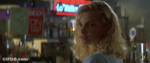 A Blonde Woman Is Smiling In Front Of A Sign That Says No Water To Tap GIF