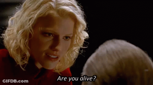 A Blonde Woman Is Talking To A Man In A Dark Room And Asking If He Is Alive . GIF