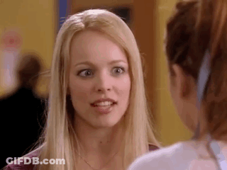 A Blonde Woman Is Talking To Another Woman In A Hallway . GIF