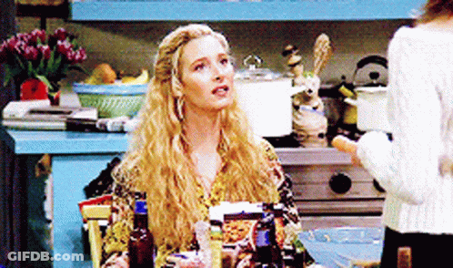 A Blonde Woman Sitting At A Table With Bottles Of Alcohol GIF