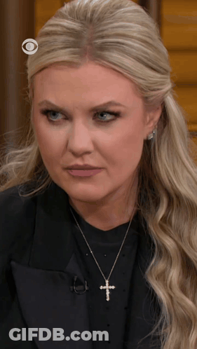 A Blonde Woman Wearing A Cross Necklace And A Black Jacket GIF