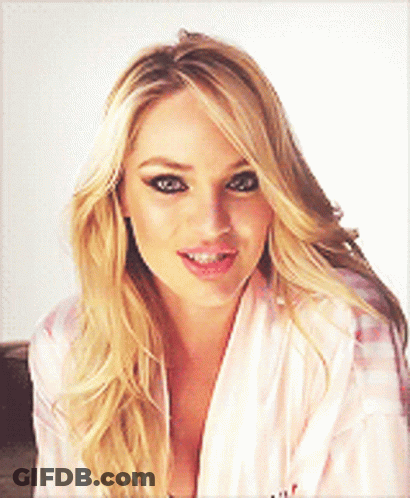 A Blonde Woman Wearing A Pink Robe Is Smiling And Looking At The Camera GIF