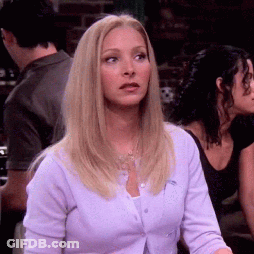 A Blonde Woman Wearing A Purple Cardigan Is Sitting At A Table With Other People . GIF