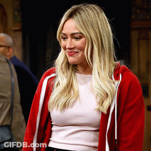 A Blonde Woman Wearing A Red Hoodie And A White Shirt Smiles GIF