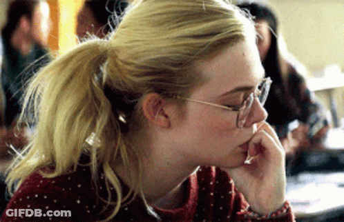 A Blonde Woman Wearing Glasses And A Ponytail Looks Down GIF