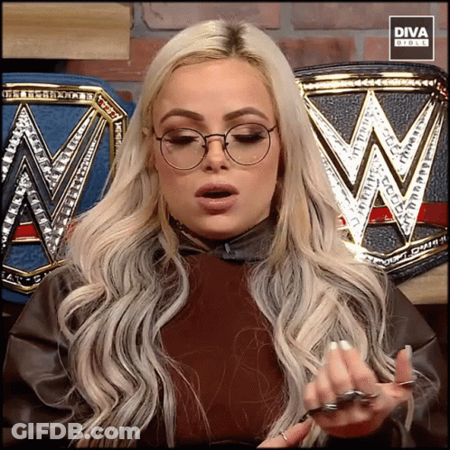 A Blonde Woman Wearing Glasses Is Standing In Front Of A Diva Branded Belt GIF