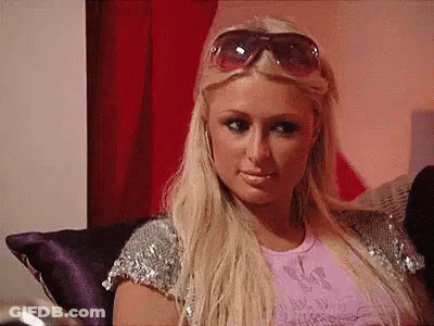 A Blonde Woman Wearing Sunglasses Is Sitting On A Couch . GIF