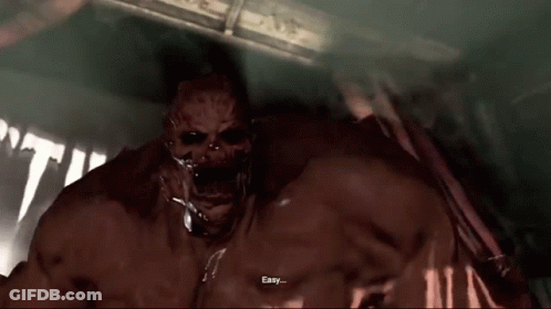 A Bloody Monster Is Standing In A Dark Room With His Arms Outstretched And His Mouth Open . GIF