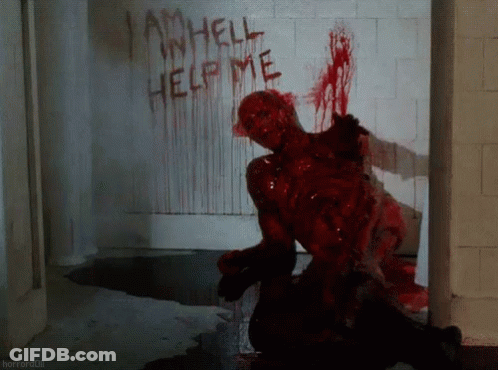 A Bloody Zombie Crawls In Front Of A Wall That Says I Am Hell Help Me GIF